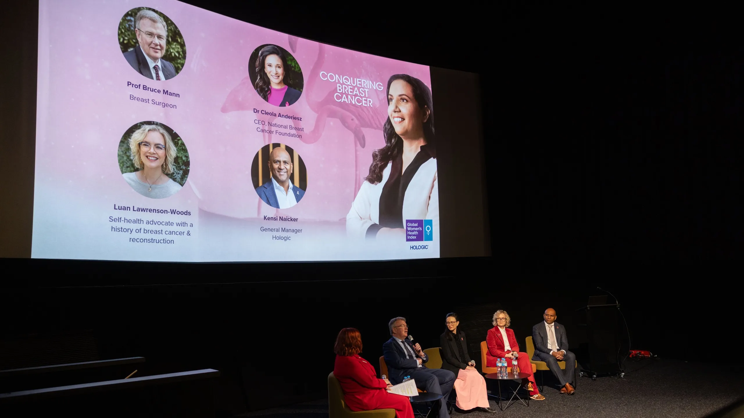 4 panelists and a moderator sitting under a presentation screen